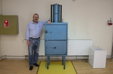 mand-læner-sig-op-af-blå-ballepresser-på-gul-gulvfirkant